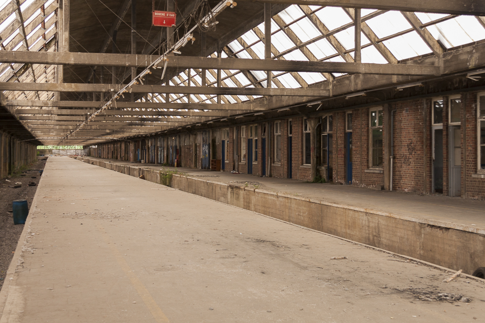 zicht op de verlaten perrons van Gare De Montzen,
            een groot vervallen station dat een bekende urbex locatie is geworden